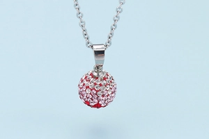Macro detail of a spherical pendant featuring red and pink gradient rhinestones and silver chain