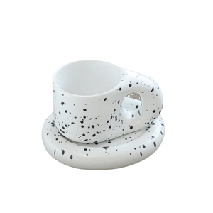 White ceramic coffee cup with black splatter pattern and thick round handle on white background