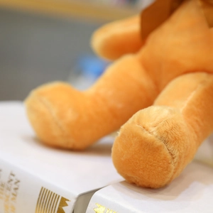 Vista detallada del suave pelaje de felpa naranja y las costuras de un oso de peluche