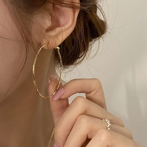 Large golden hoop earrings with textured finish shown on model for elegant daily look