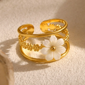 Detail of 18K gold plated layered ring featuring a white flower and beaded texture band
