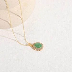 Macro view of emerald zircon pendant necklace in gold finish with white diamond accents