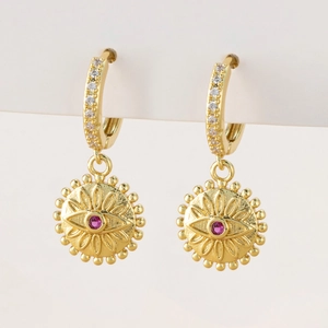 Macro shot of gold-plated hoop earrings with micro-set zircon and red gemstone detail
