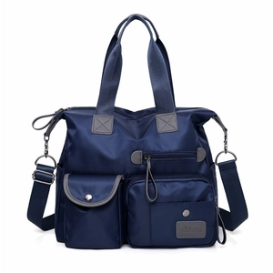 Macro detail of navy blue nylon travel bag with multiple pockets and leather logo