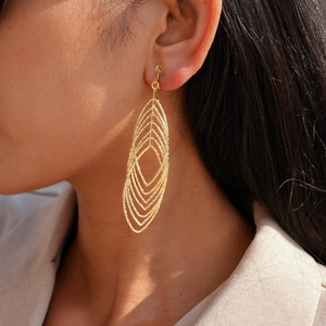Macro view of gold geometric layered leaf-shaped ear cuffs on a model's ear