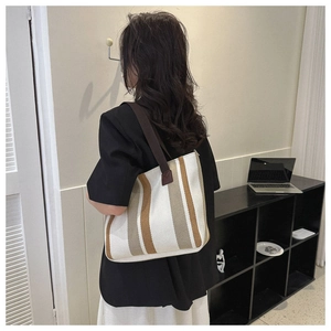 Detail of striped canvas tote bag with brown straps and leather reinforcement stitching