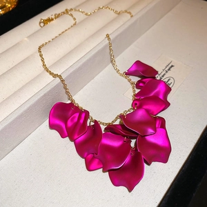 Detail view of a magenta petal fringe pendant with a gold chain on a white display tray