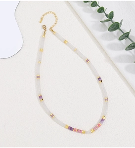 Macro detail of natural stone beaded necklace with gold lobster clasp and extension chain