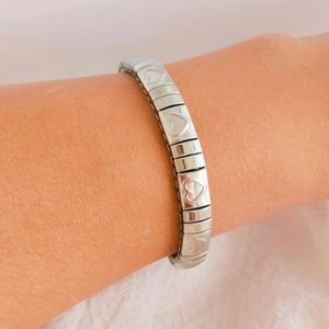 Detailed view of silver stainless steel stretch bracelet with engraved heart patterns