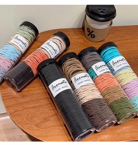 Assorted colorful seamless hair ties set in transparent tubes on a wooden table