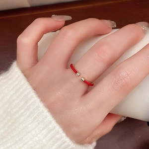 Detailed view of snake-shaped red rope open ring on finger with soft lighting