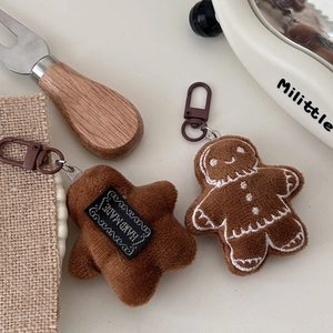 Detail of plush gingerbread man and star keychain with handmade label and metal clip