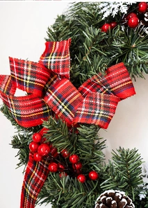 Close-up of Nordic Christmas wreath with pine cones, red berries and plaid bow decoration
