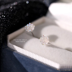 Macro detail of S925 sterling silver rose earring on blue velvet jewelry box