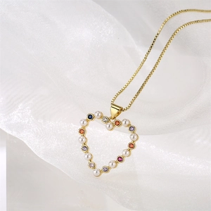 Détail du collier cœur doré orné de zircons colorés et de perles blanches élégantes