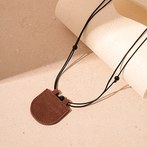 Detail of brown suede leather pouch pendant with black cord and silver accents