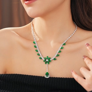 Close-up of a luxury silver flower necklace with green zircons and a teardrop pendant
