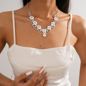 Detail of layered floral necklace with rhinestones and pearlescent drop on model
