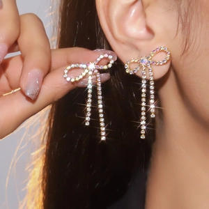 Detailed macro view of sparkling rhinestone bow earrings with long shimmering tassels
