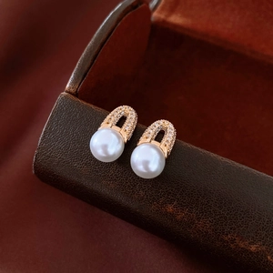 Macro shot of 18K gold plated geometric earrings with crystal pave and white pearl drop
