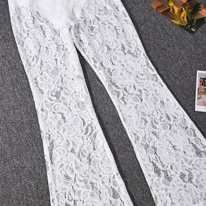 Flat lay of white floral lace flared trousers with intricate mesh details on a grey texture
