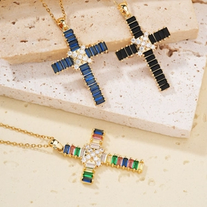 Detail view of gold cross necklaces with colorful, blue and black zircon stones on a rock surface