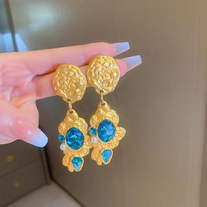 Close-up of vintage gold flower earrings with blue crystal drops and white pearls
