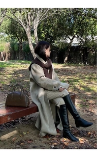 Close-up of a stylish winter shawl hood paired with a beige wool coat in an outdoor park