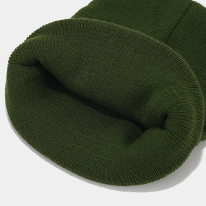 Detailed close-up showing the dense knit texture of the dark green cuffed beanie cap