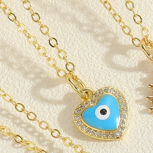 Macro detail of gold heart pendant with light blue evil eye and zircon crystals