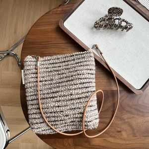 Detail of vintage striped tweed crossbody bag with slim leather strap on wooden surface