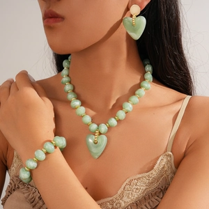 Detail of green acrylic beaded heart pendant necklace and earrings on model