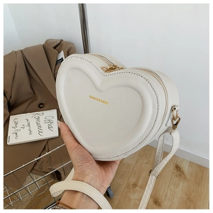Dettaglio della borsa a tracolla crema a forma di cuore con scritta Fashion & Bag e pelle