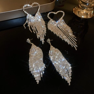 Macro shot of silver heart-shaped tassel earrings with sparkling rhinestones details