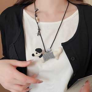 Detailed view of handmade ceramic fabric dachshund dog pendant on a woven black necklace