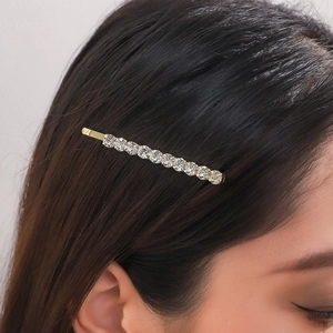 Close-up of gold rhinestone hair pin accessory on dark hair with sparkling crystal detail