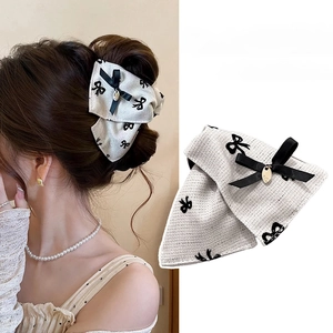 Elegant white tweed hair claw with black bow print and gold pendant shown on a model