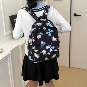 Fashionable black backpack with daisy and butterfly prints worn by a model in a room