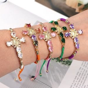 Close-up of five colorful braided rope cross bracelets with zircon inlays and Mary icon