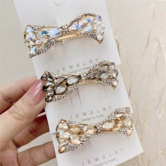 Sparkling crystal bow hair clip detail in iridescent white, grey, and champagne gold