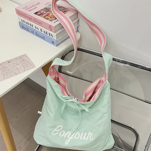 Détail du sac cabas vert menthe avec bandoulière rayée rose et décoration nœud élégant