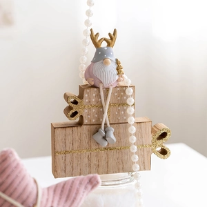 Pink and grey Christmas gnome with reindeer antlers on wooden gift box bases for desk decor