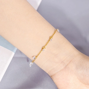 Detail of minimalist gold chain bracelet with clear zircon charms on model wrist