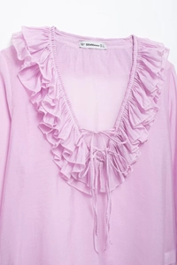 Close-up of lilac V-neck blouse with ruffle trim, tie details and light textured fabric