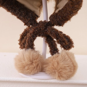 Dettaglio del berretto invernale in peluche marrone con pompon in pelliccia e fodera