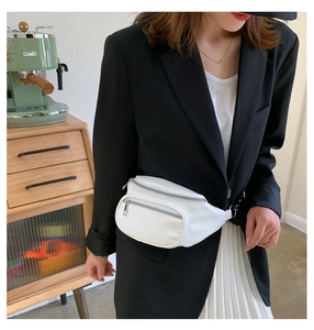 Detailed view of a white minimalist waist bag with three zippers worn by a model
