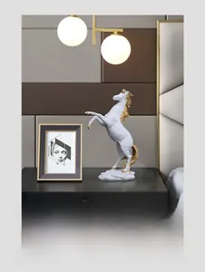 Detailed view of white resin horse sculpture with gold accents on a modern bedside table