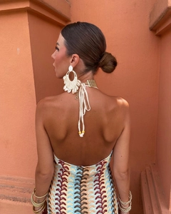 Détail macro de boucles d'oreilles en coquillage tissé avec une robe de plage dos nu chic