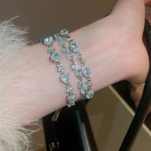 Macro shot of silver bow bracelets with aquamarine stones and heart-shaped charms