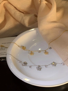 Close-up of gold and silver flower anklets with zircon crystals in a decorative dish